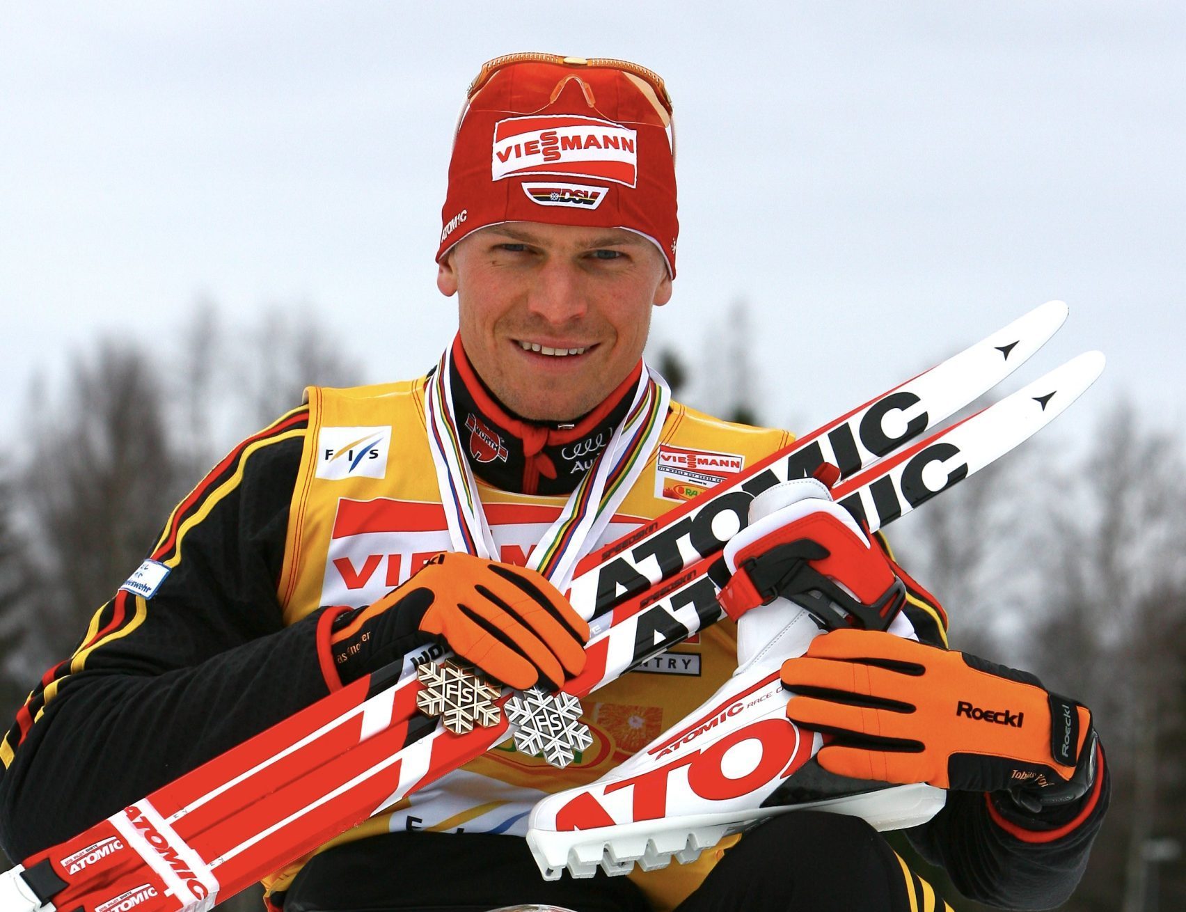 Tobias Angerer im Schnee mit Skiern und Troph&auml;en